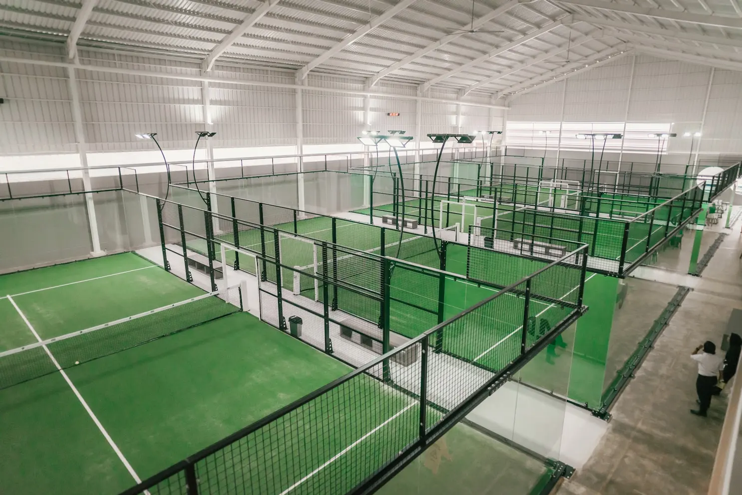 Rows of glass padel courts seen from the upper level