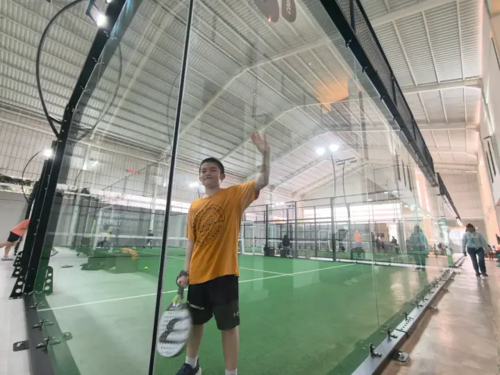 Player reaching for an overhead behind the glass